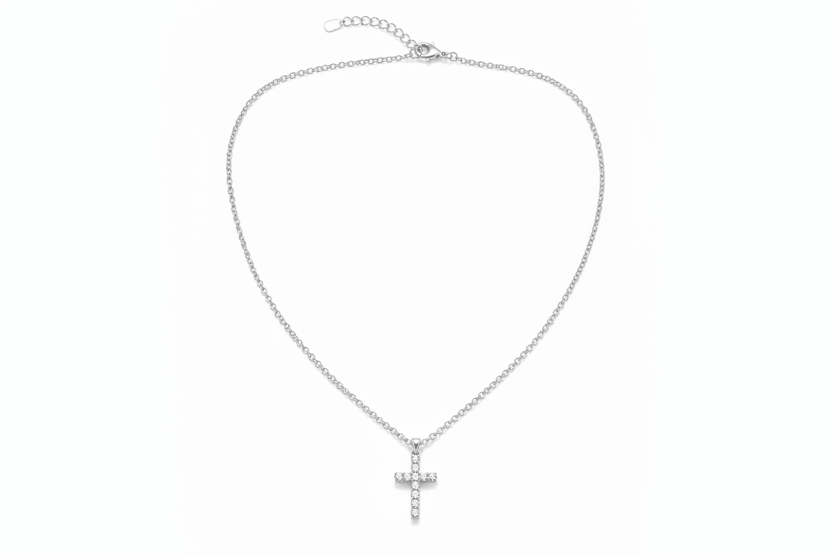 A delicate gold chain necklace with a small cross pendant adorned with clear rhinestones, displayed against a solid white background.