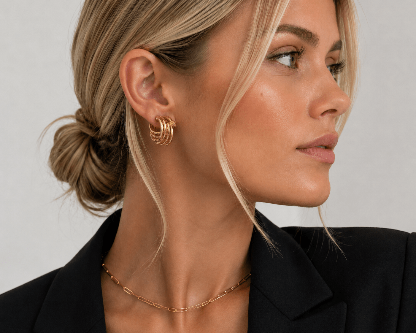 Close-up of a woman's ear wearing the Genevieve Gold Ribbed Knot Earring.