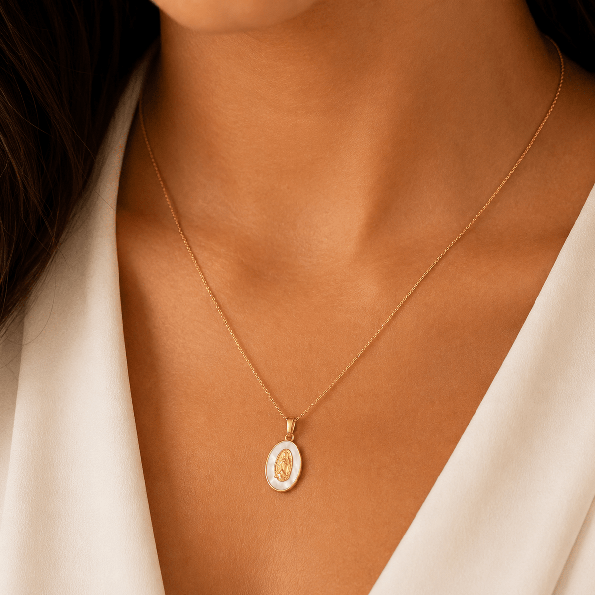 A woman wearing the Guadalupe Gold Pearl Necklace, close-up of the mother-of-pearl medallion pendant.