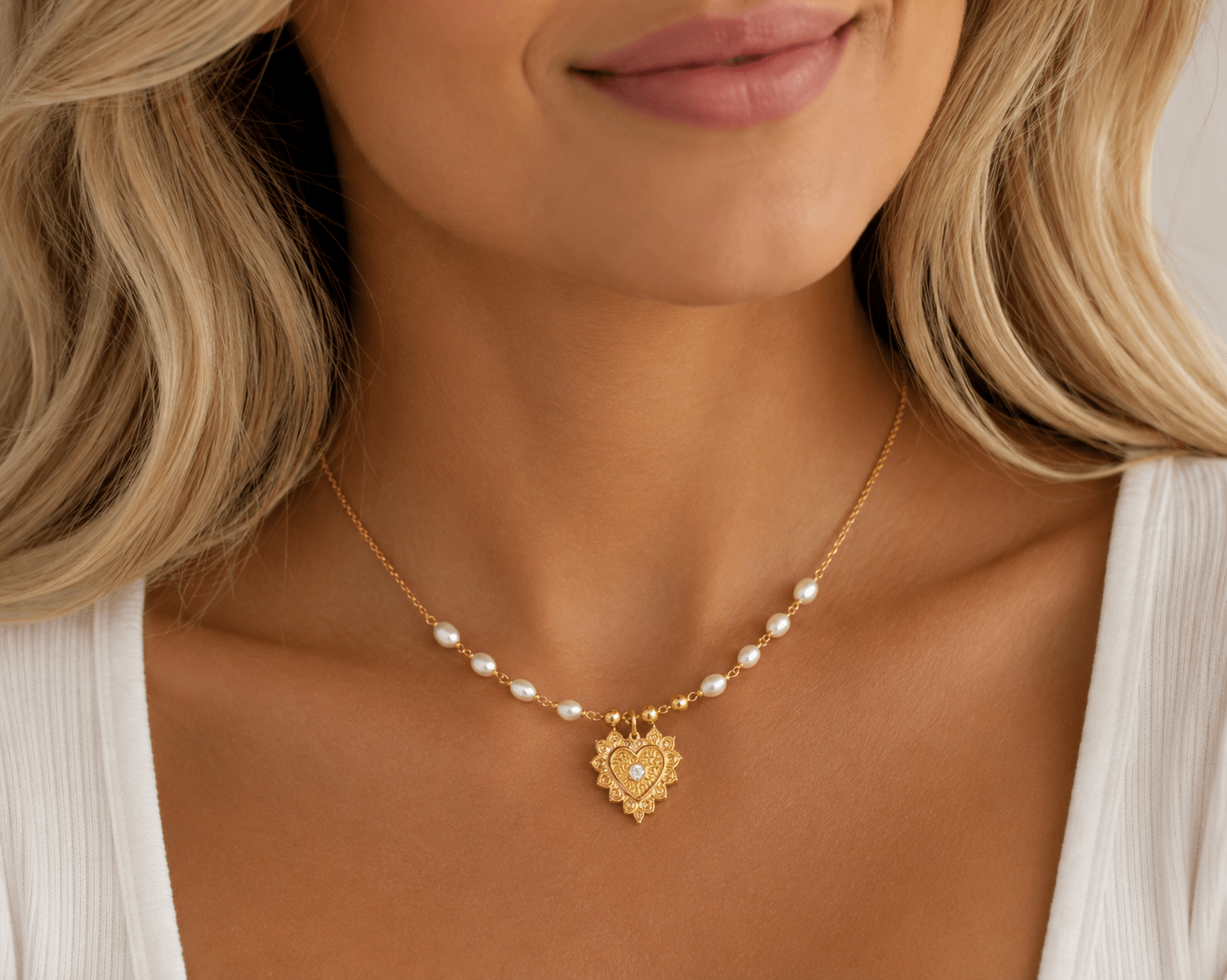 Ava gold pearl necklace with heart pendant worn at the collarbone to show pendant size and chain length